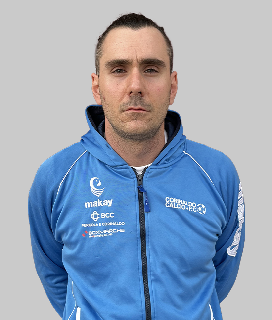 Ritratto frontale di membro dello staff/allenatore con felpa azzurra Corinaldo Calcio F.C., zip e loghi sponsor, su sfondo grigio neutro